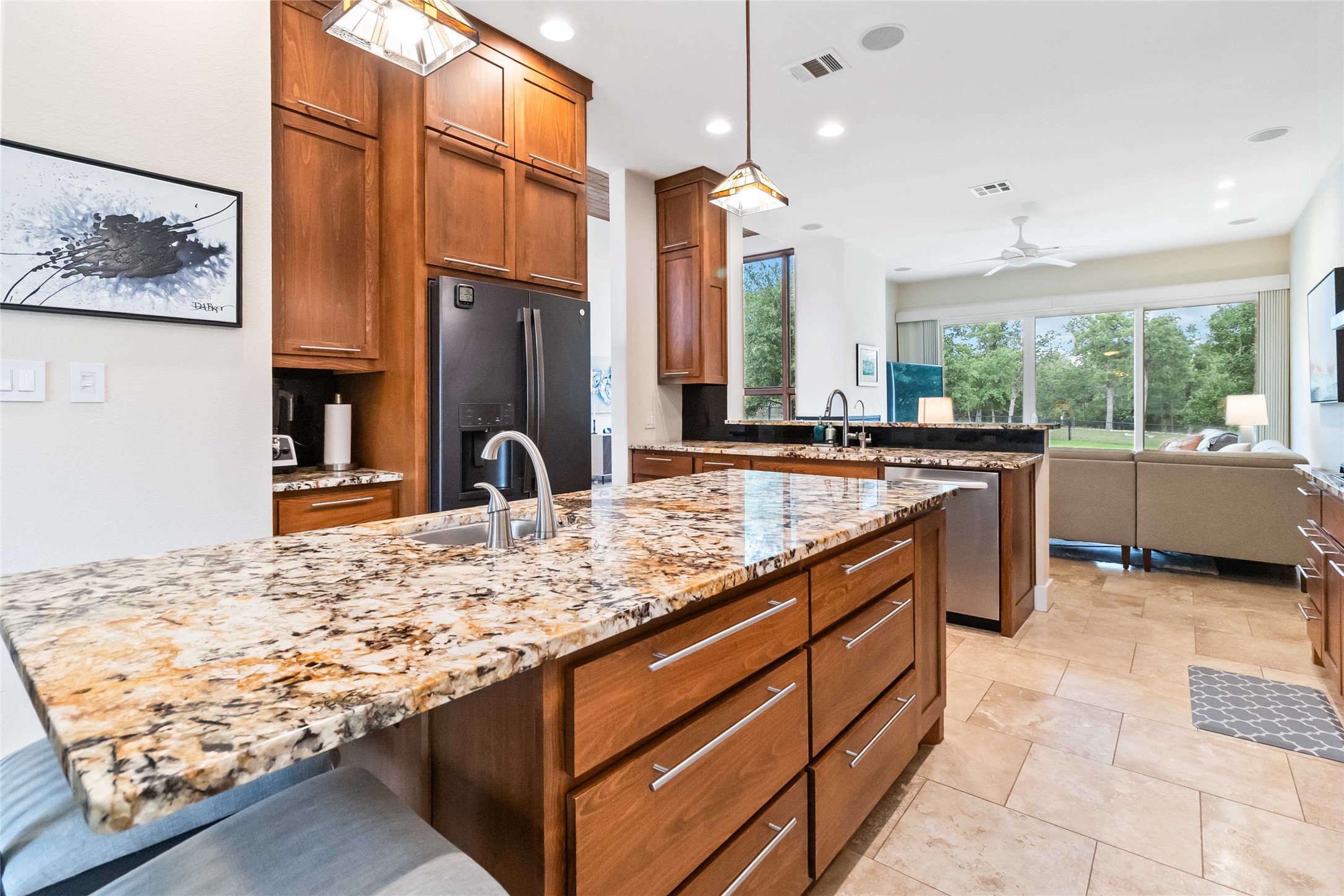 129 Powder Horn Road Bastrop, TX 78602 - Photo 11 of 27 Kitchen featuring brown cabinetry, light stone countertops, decorative light fixtures, black fridge with ice dispenser, and recessed lighting