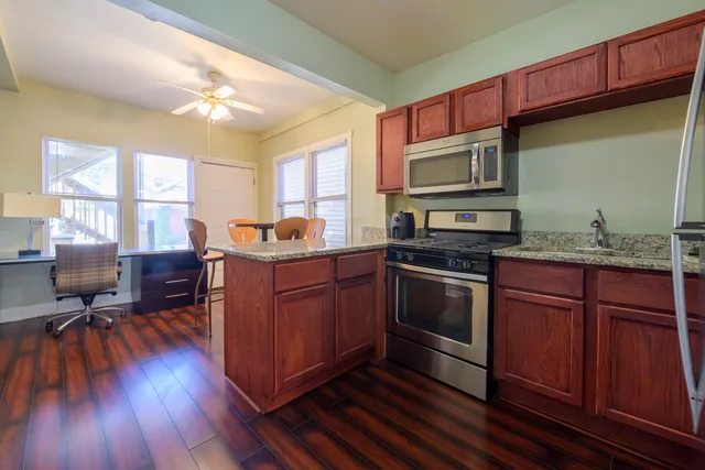 a kitchen with granite countertop wooden floors appliances and cabinets