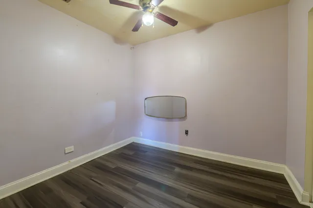 an empty room with wooden floor and fan