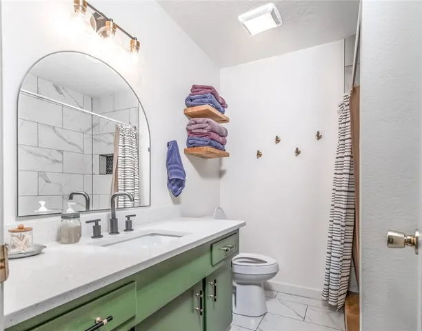 a bathroom with a granite countertop sink mirror vanity and toilet