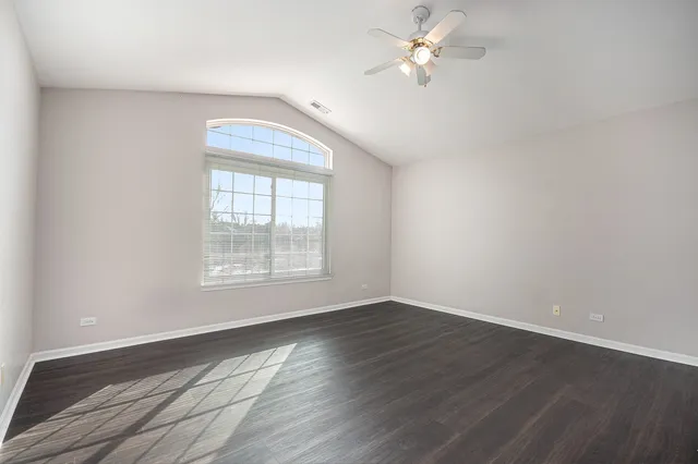 an empty room with wooden floor fan and windows