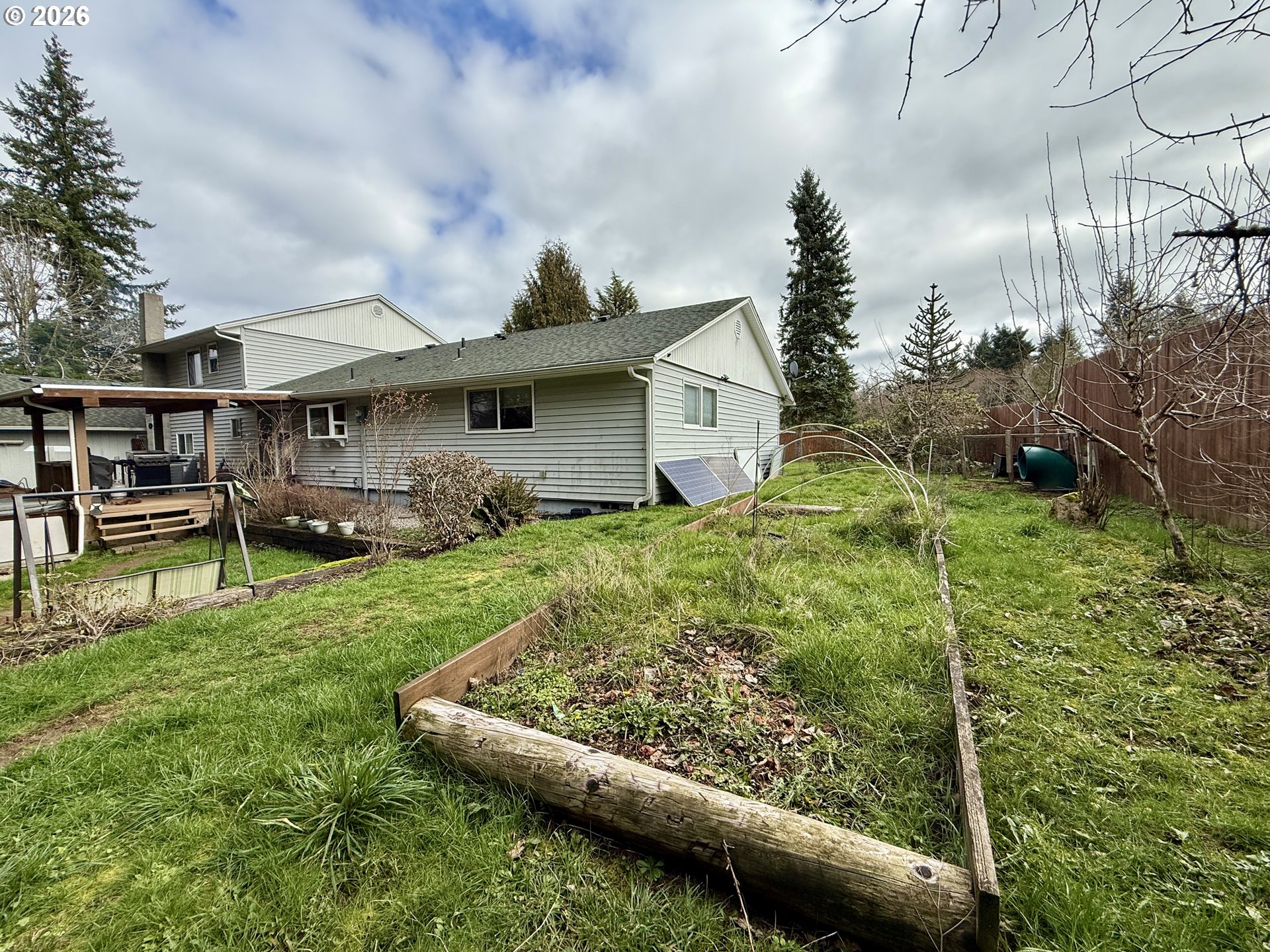 105 Timberline Drive Castle Rock, WA 98611 - Photo 21 of 21 a view of a garden with a bench in front of the house