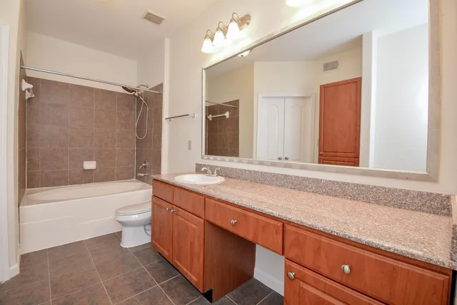 a bathroom with a granite countertop sink a toilet a bathtub and shower