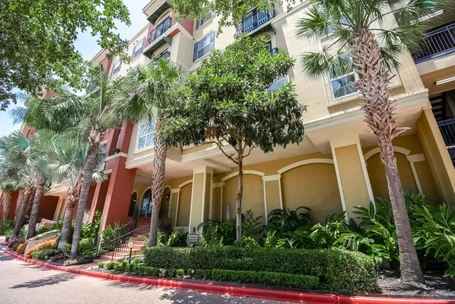 a front view of a multi story residential apartment building with yard and green space