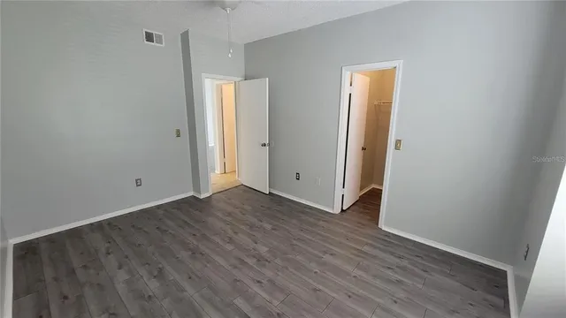 a view of an empty room with wooden floor and closet