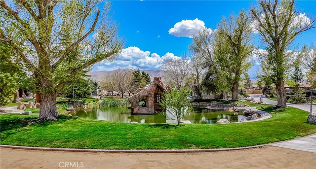 a view of a fountain in front of a brick house with large windows