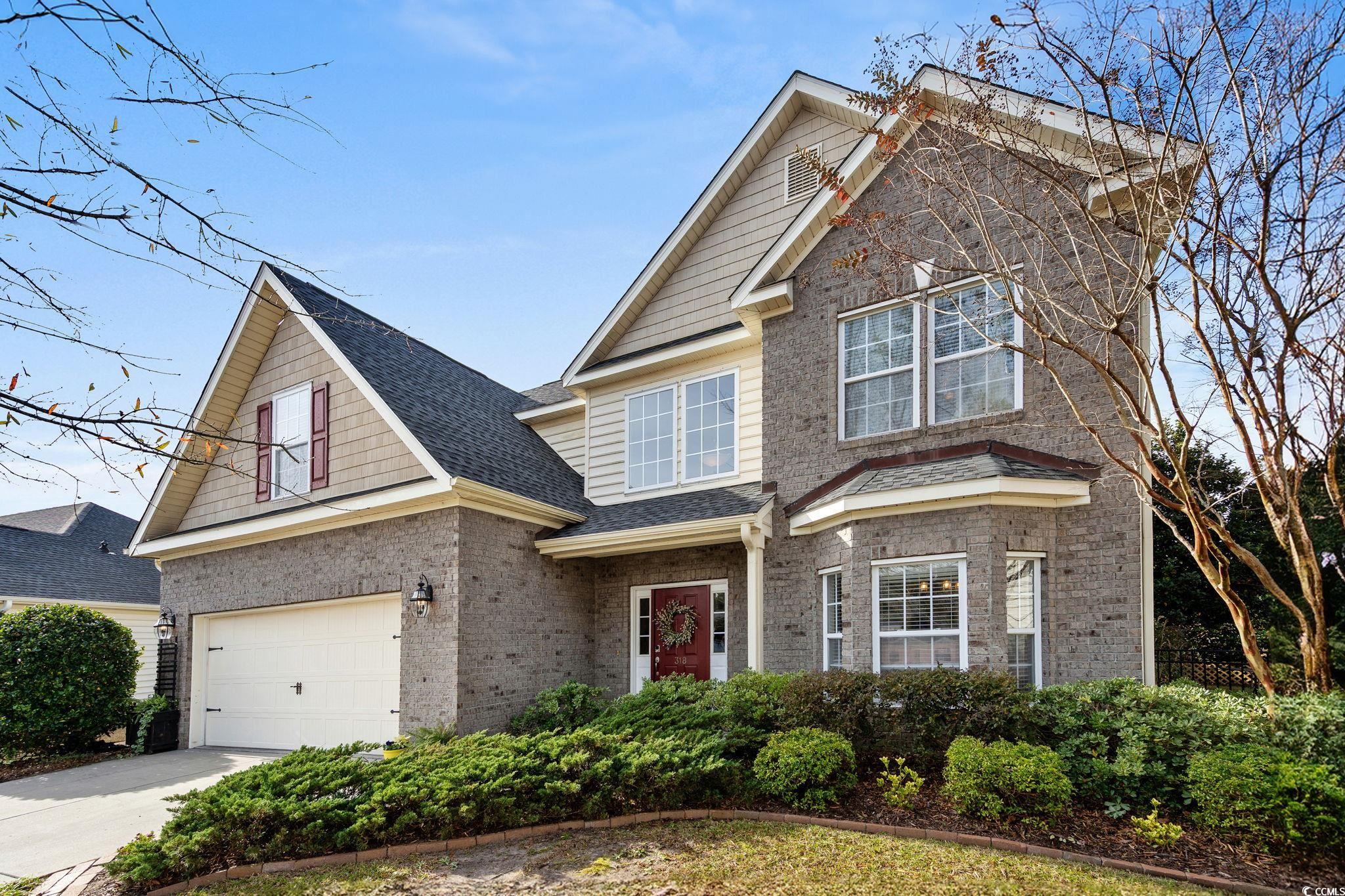 Traditional-style house with brick siding, driveway, roof with shingles, and a garage