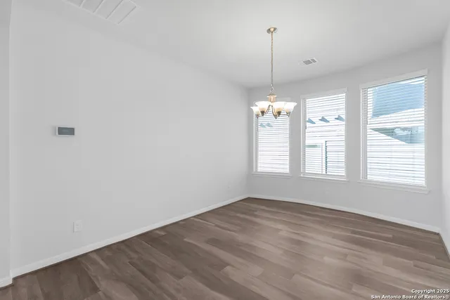 a view of a room with wooden floor ceiling fan and window