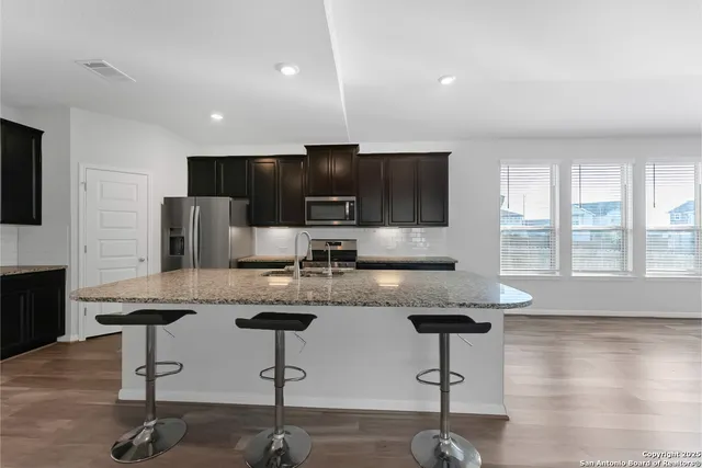 a kitchen with stainless steel appliances granite countertop a stove a sink a refrigerator and a counter space