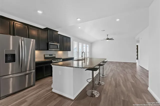 a kitchen with kitchen island wooden floors appliances and cabinets