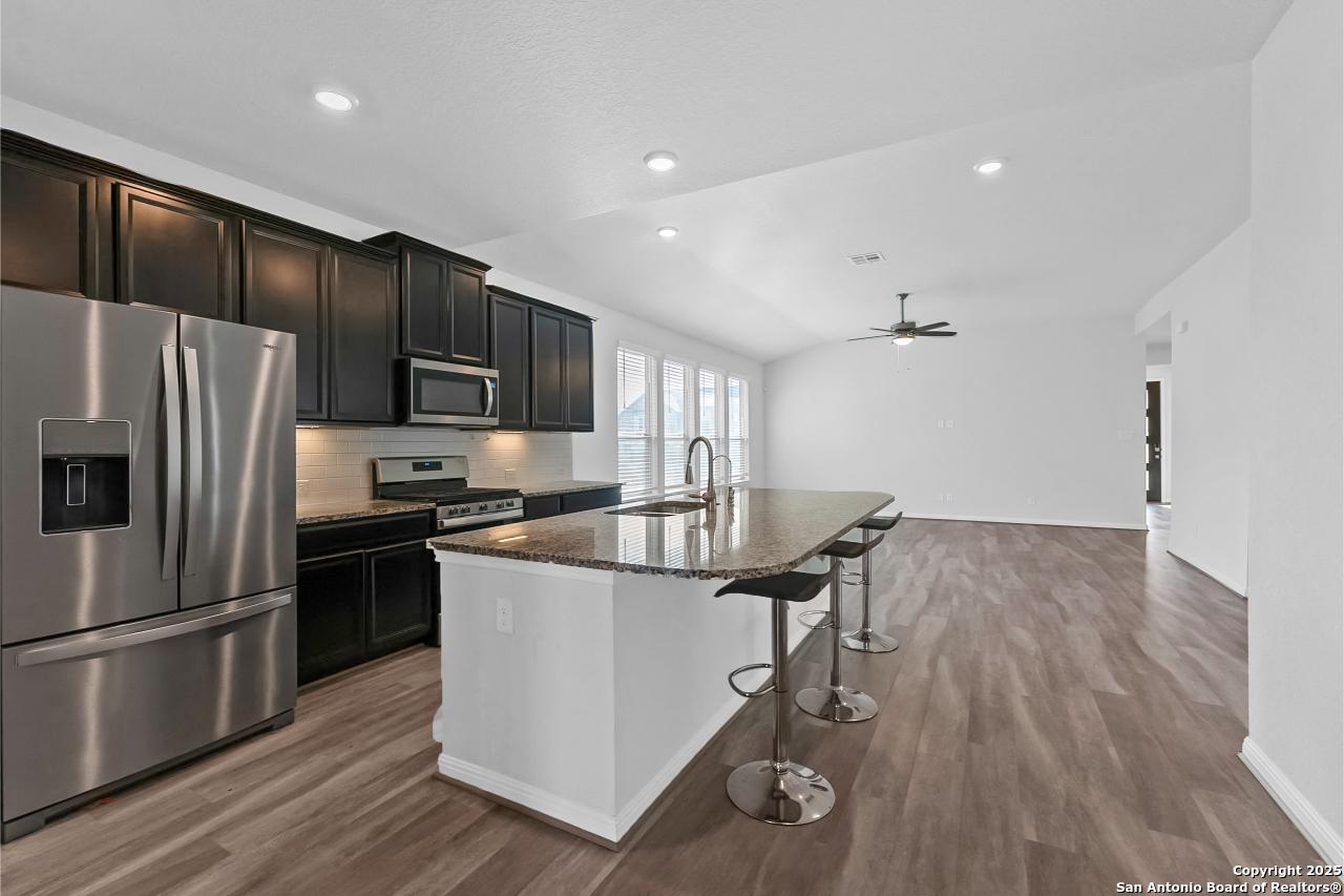 13223 Prospector Way St. Hedwig, TX 78152 - Photo 15 of 30 a kitchen with kitchen island wooden floors appliances and cabinets