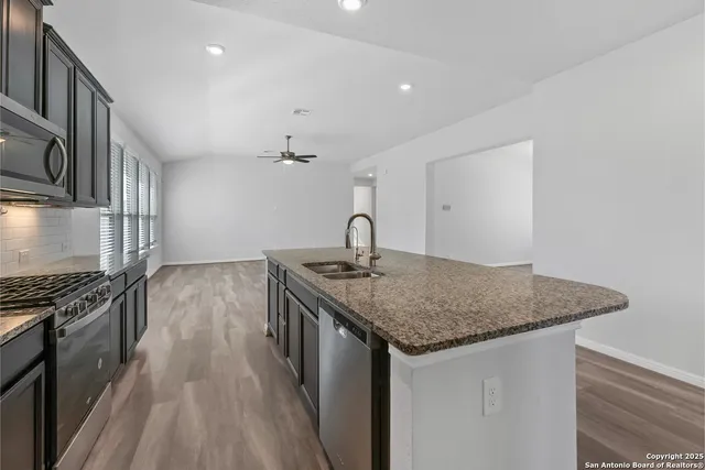 a kitchen with stainless steel appliances granite countertop a sink stove and cabinets