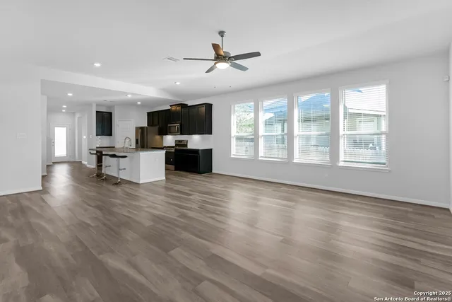 a view of a kitchen with furniture a ceiling fan and wooden floor