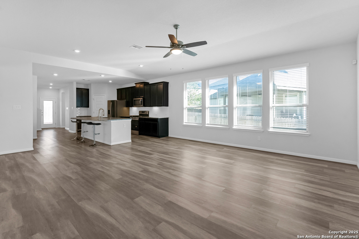 13223 Prospector Way St. Hedwig, TX 78152 - Photo 8 of 30 a view of a kitchen with furniture a ceiling fan and wooden floor