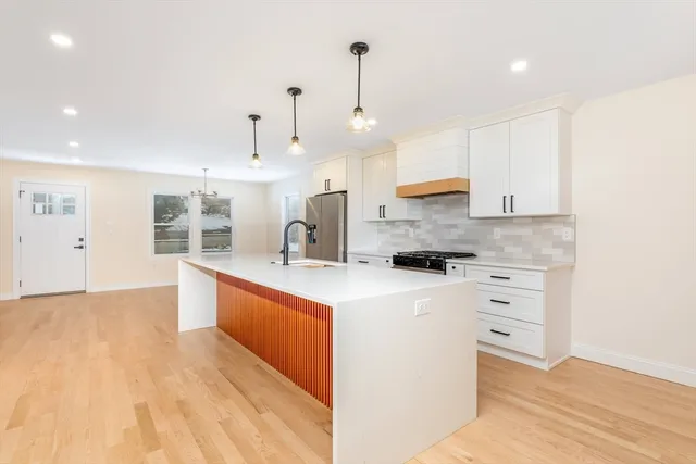 a large kitchen with stainless steel appliances a large counter top a stove a refrigerator and a sink