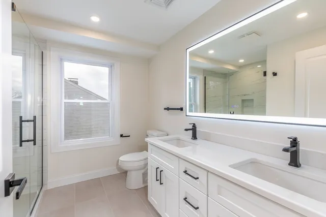 a bathroom with a double vanity sink toilet and shower