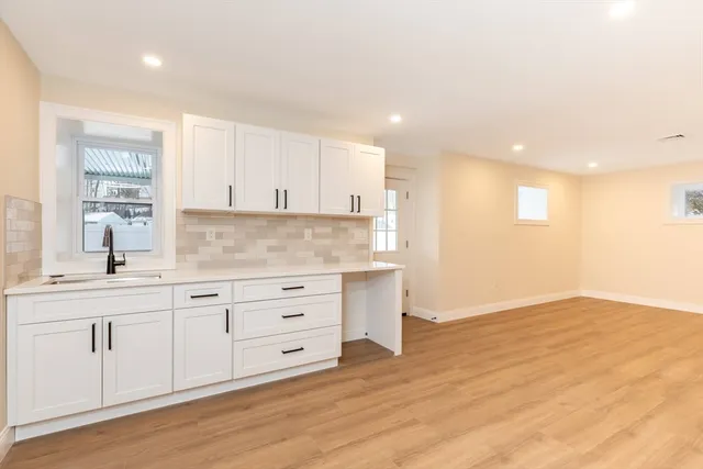 a kitchen with granite countertop white cabinets and wooden floor