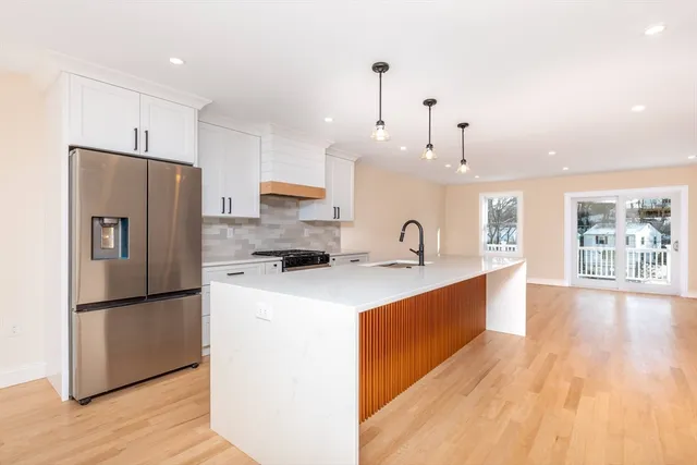 a large kitchen with stainless steel appliances a refrigerator and a wooden floor