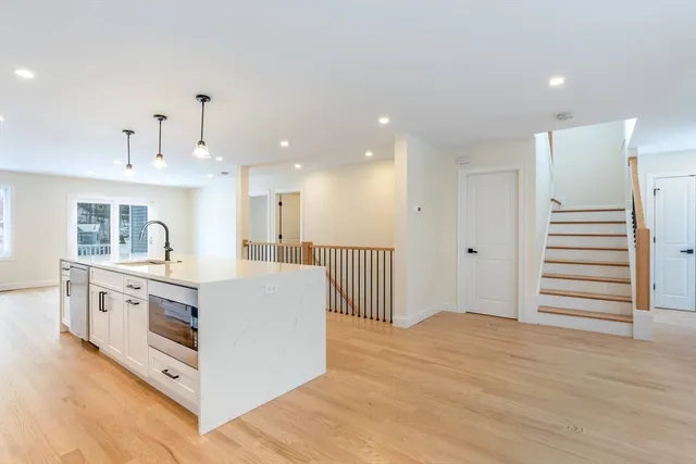 a large white kitchen with wooden floors and stainless steel appliances