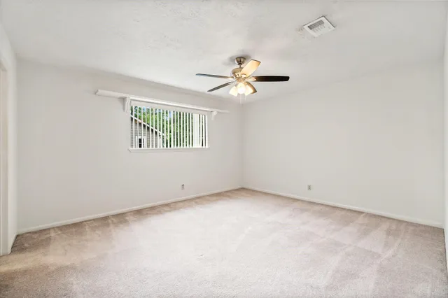 an empty room with windows and ceiling fan