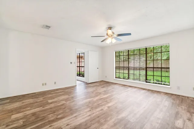 a view of an empty room with a window and wooden floor