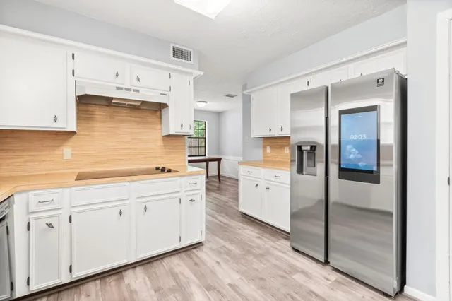 a kitchen with white cabinets and sink