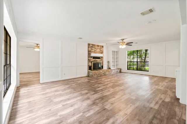 a view of an empty room with a window and a kitchen