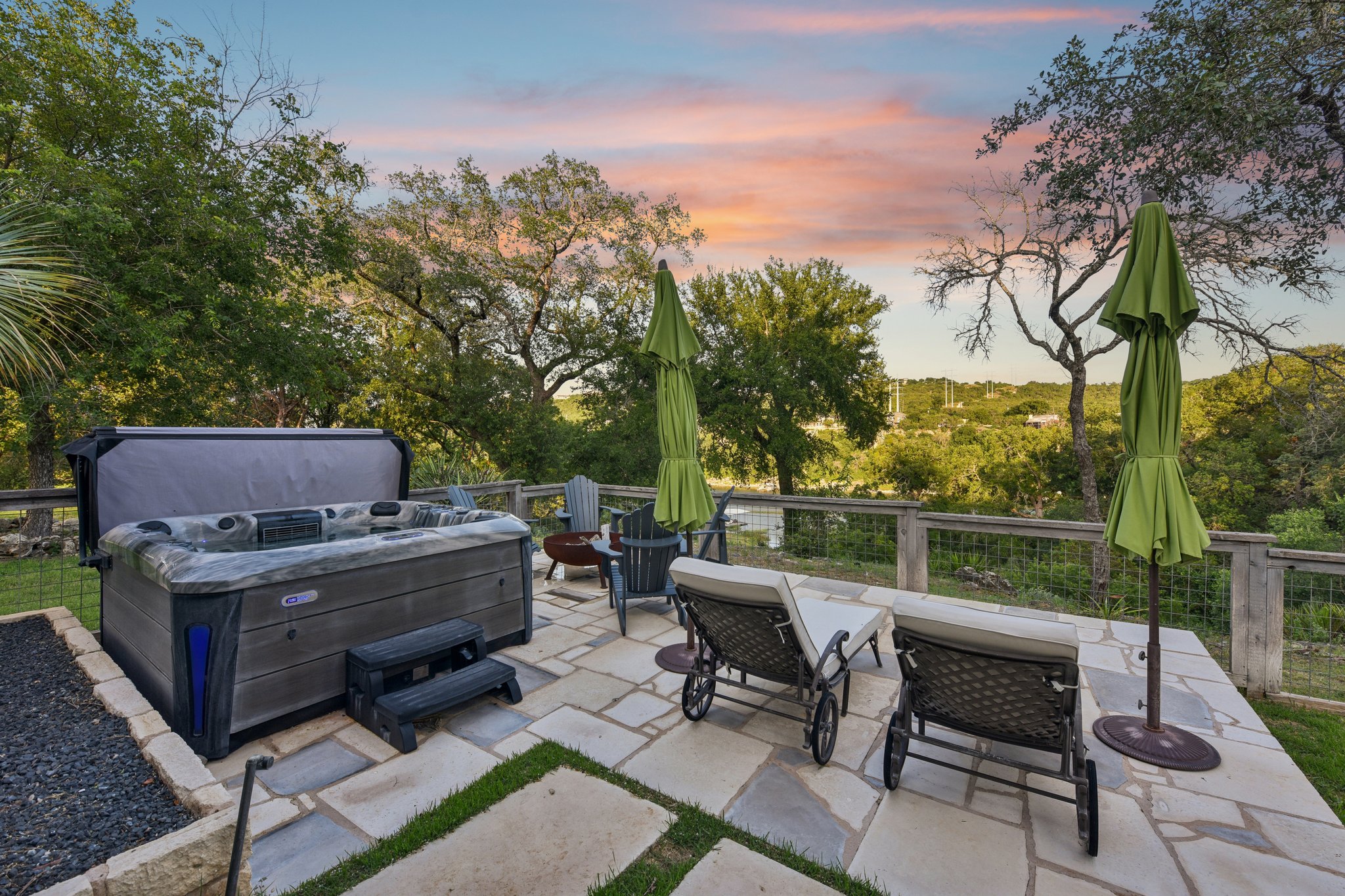 2203 Improver Road Spicewood, TX 78669 - Photo 12 of 38 Relax in the spa on a private stone patio, offering a tranquil view of the surrounding trees and distant landscape.