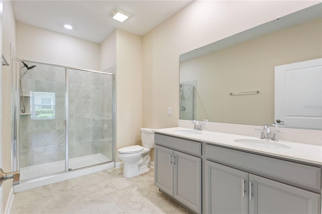1064 Blackwolf Run Road Davenport, FL 33896 - Photo 14 of 38 a bathroom with a double vanity sink toilet and shower