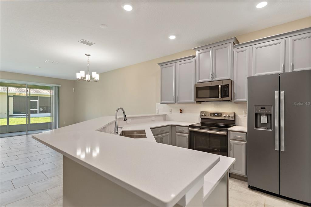 1064 Blackwolf Run Road Davenport, FL 33896 - Photo 3 of 38 a kitchen with stainless steel appliances a sink stove refrigerator and cabinets