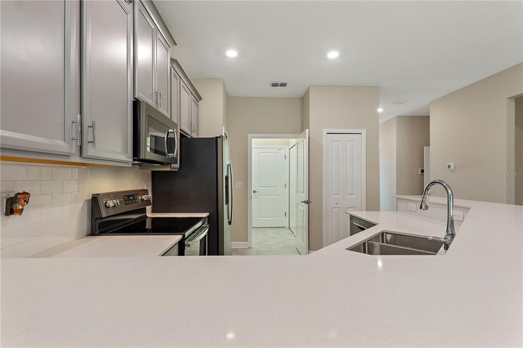 1064 Blackwolf Run Road Davenport, FL 33896 - Photo 4 of 38 a kitchen with stainless steel appliances kitchen island granite countertop a refrigerator and a sink