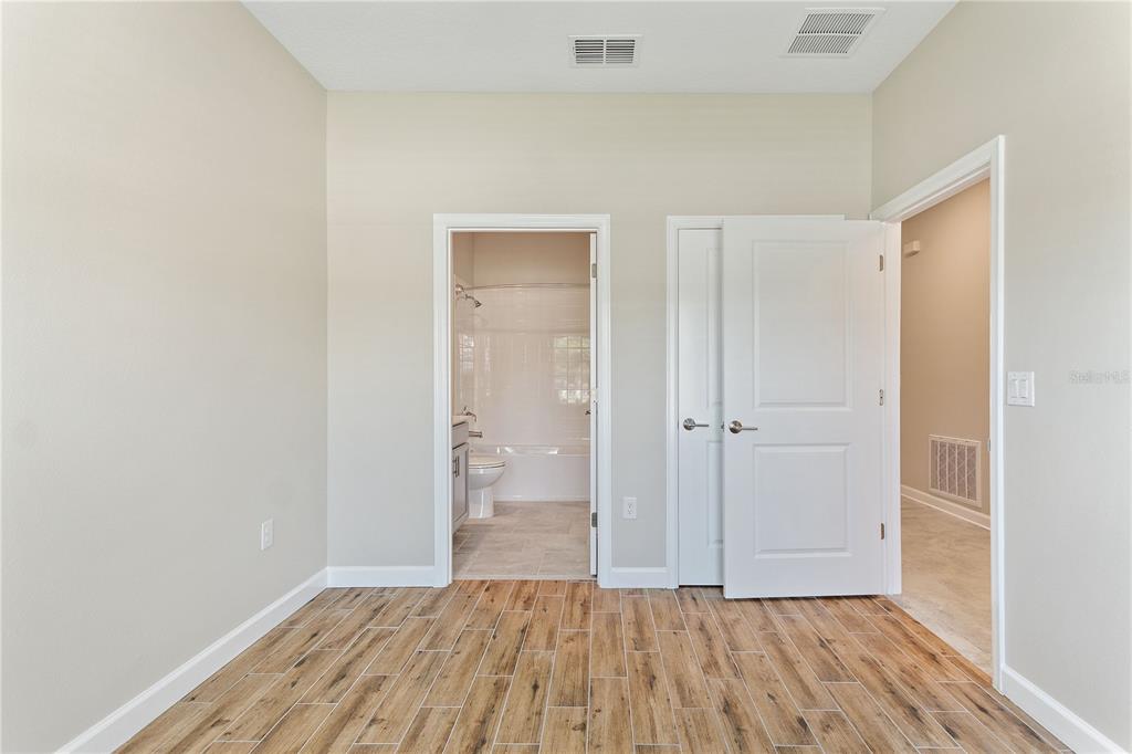 1064 Blackwolf Run Road Davenport, FL 33896 - Photo 7 of 38 a view of an empty room with wooden floor and a bathroom