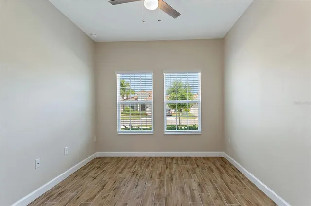 an empty room with wooden floor and windows