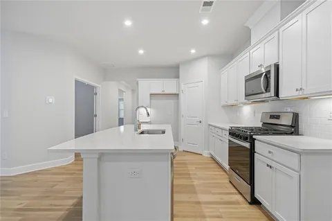 a kitchen with stainless steel appliances a sink dishwasher stove refrigerator and cabinets with wooden floor