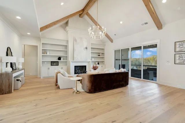 a living room with furniture kitchen view and a chandelier