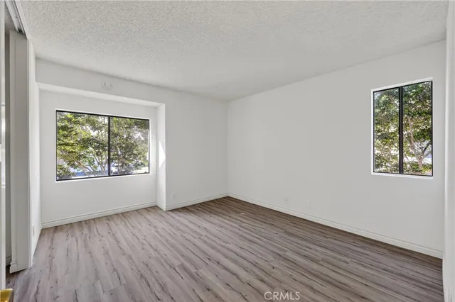 an empty room with wooden floor closet and windows