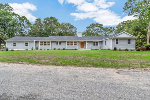 a view of a house with a big yard and large trees