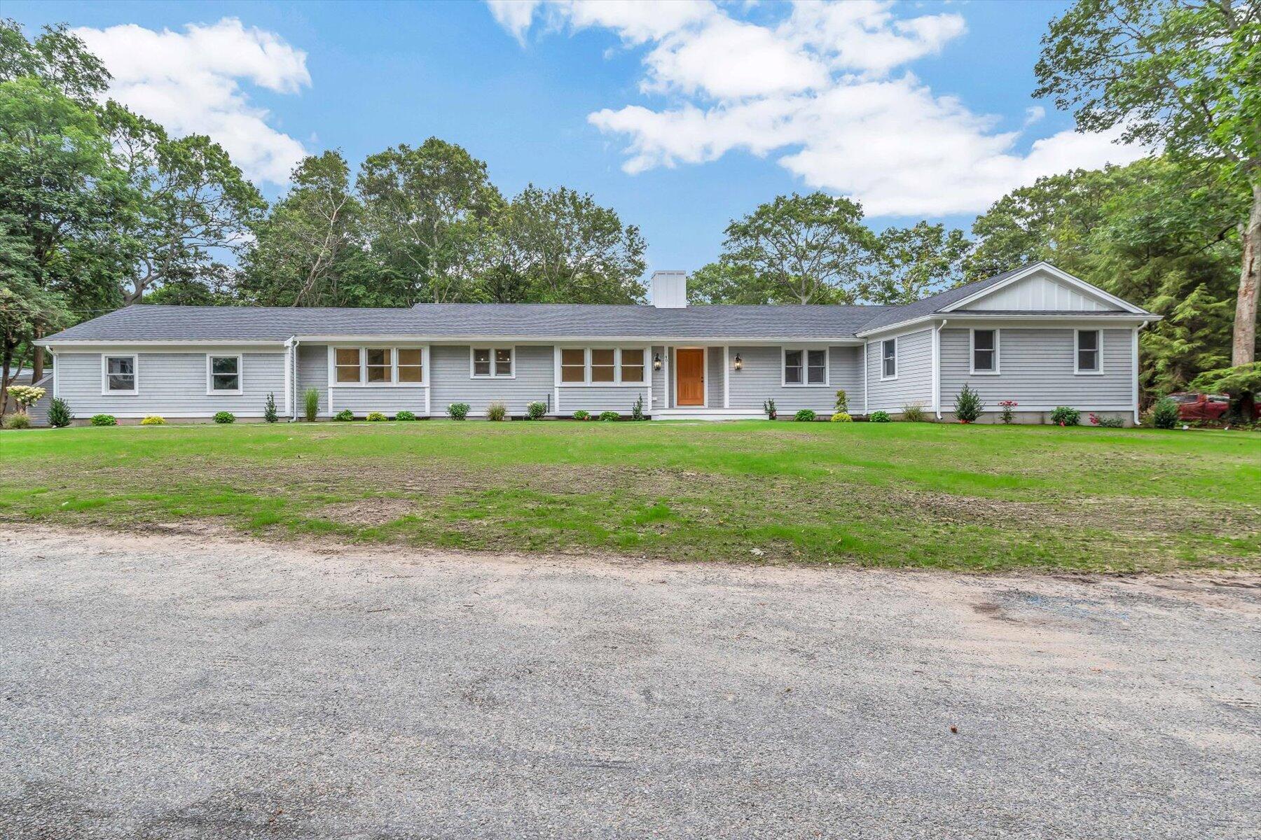 a view of a house with a big yard and large trees