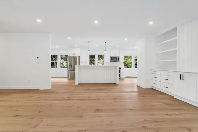 a view of an empty room with wooden floor and windows