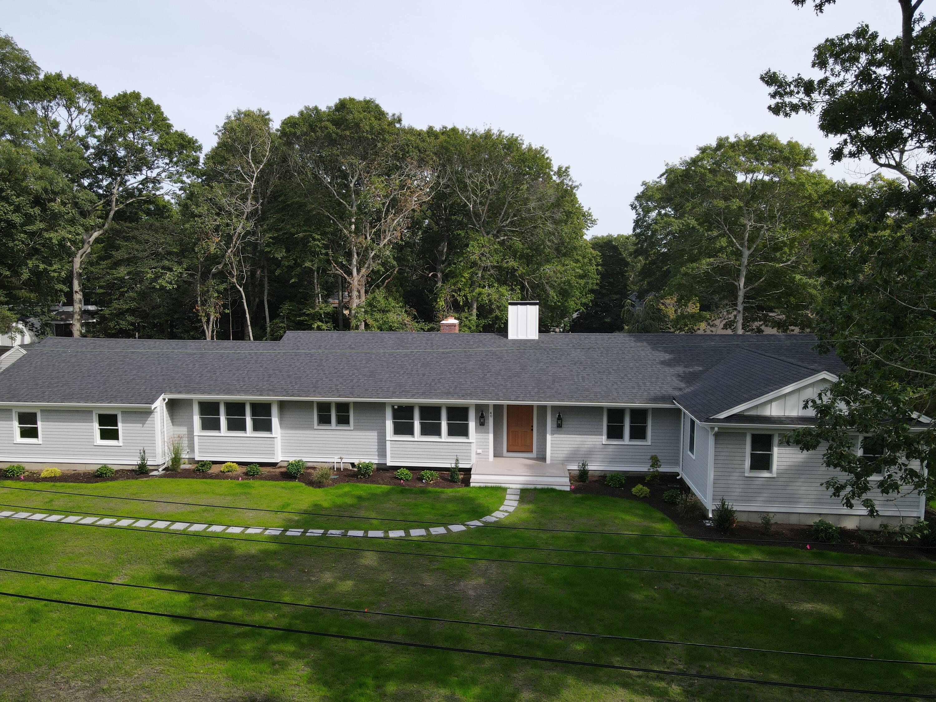 40 Sachem Drive Centerville, MA 02632 - Photo 6 of 56 a view of a white house with a big yard and potted plants and large trees