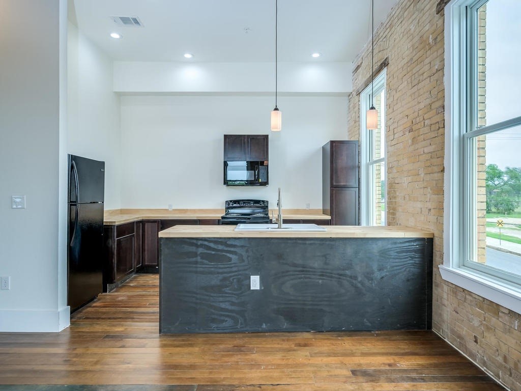 110 South Main Street, Unit 201 Elgin, TX 78621 - Photo 6 of 19 a view of kitchen with stainless steel appliances granite countertop cabinets and wooden floor