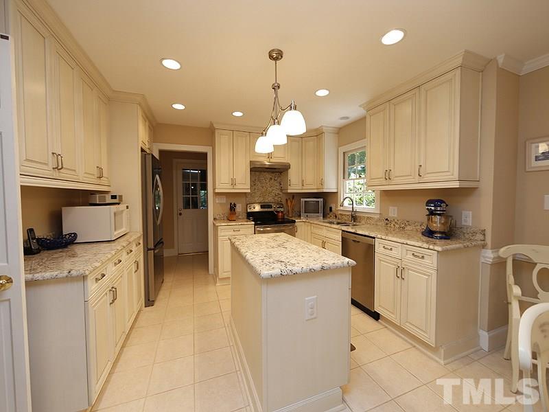 8904 Wellsley Way Raleigh, NC 27613 - Photo 8 of 25 a kitchen with granite countertop a sink stove refrigerator and white cabinets with wooden floor