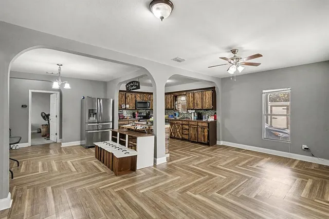 a living room with furniture a chandelier and kitchen view
