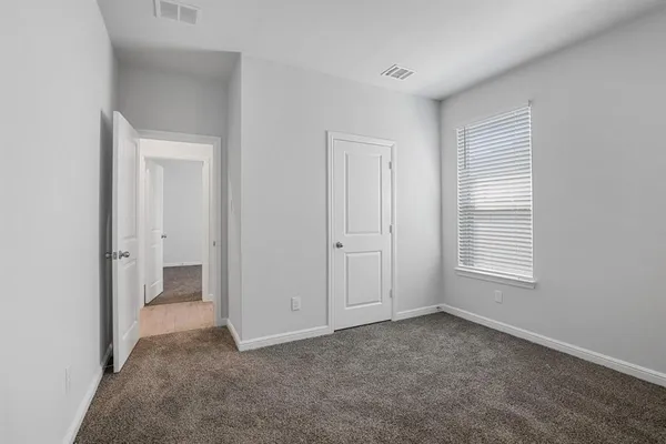 a view of an empty room with closet and a window