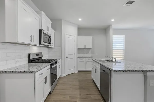 a kitchen with stainless steel appliances granite countertop a stove a sink and a refrigerator