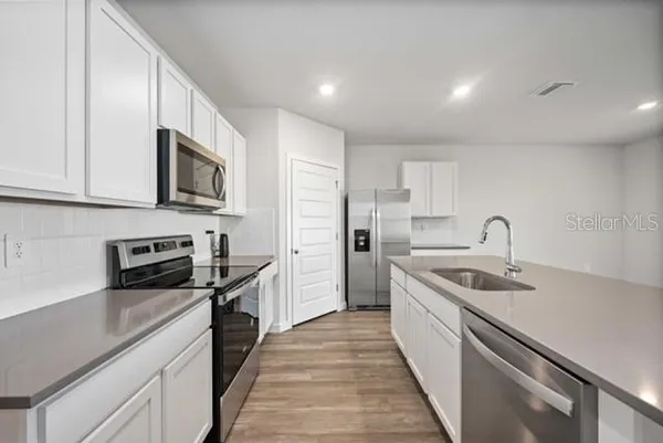 a kitchen with stainless steel appliances granite countertop a sink and dishwasher a stove top oven with wooden floor