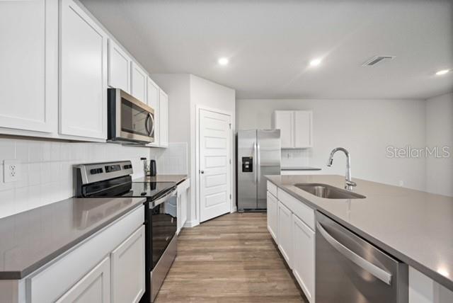 3703 Hatchery Way Lakewood Ranch, FL 34211 - Photo 12 of 35 a kitchen with stainless steel appliances granite countertop a sink and dishwasher a stove top oven with wooden floor