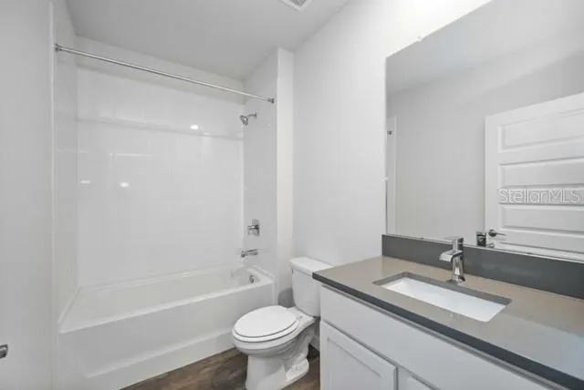 a bathroom with a granite countertop sink toilet mirror and bathtub