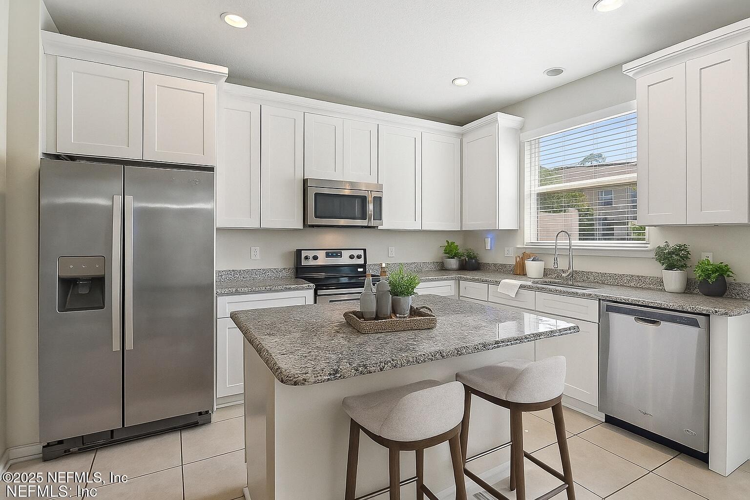 53 Nelson Lane St. Johns, FL 32259 - Photo 2 of 37 a kitchen with kitchen island granite countertop a table chairs microwave and refrigerator