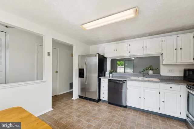 a kitchen with white cabinets and refrigerator